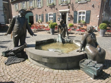 Meerbusch - Lank-Latum ( Lank ) : Hauptstraße, die Bronzeskulpturen am Lanker Marktbrunnen zeigen drei Lank-Latumer Originale, es sind Stina, Trina und Drickes. Gestaltet von Michael Franke Erkelenz.